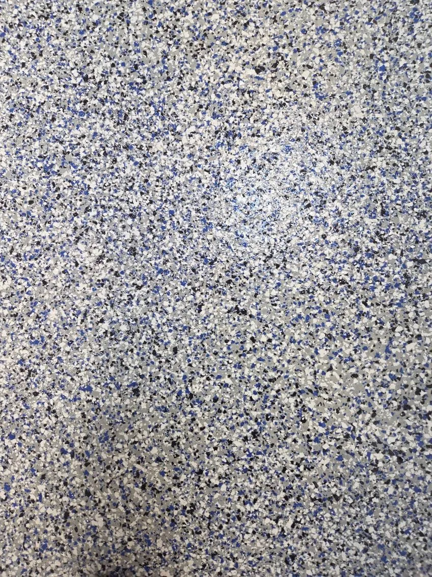 Close-up of a blue, grey, and white flake epoxy floor surface